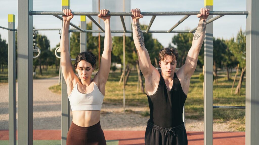 Pratiquant en dead hang, suspendu bras tendus à une barre de traction