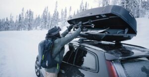 Coffre de toit Thule fermé et sanglé sur les barres d'une voiture familiale